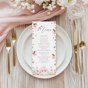 May include: A whimsical menu card with a fairy theme. The card features a delicate floral border, illustrations of fairies, and a menu with sections like "Pixie Bites" and "Woodland Treats." The card is set on a white plate with gold cutlery.