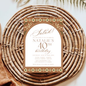 May include: A white invitation with a brown border and floral design. The invitation reads "Salud!" and invites guests to celebrate Natalie's 40th birthday. The invitation includes the date, time, and location of the event. RSVP information is also included.