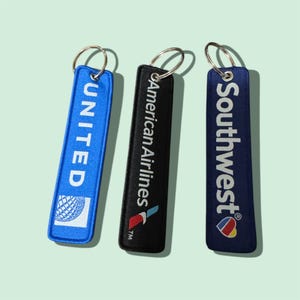 May include: Three rectangular keychains with metal rings. One is blue with "UNITED" and a globe logo, another is black with "American Airlines", and the third is navy with "Southwest" and a heart logo.