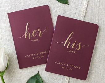 May include: Two burgundy vow books with gold lettering. The book on the left says "her vows" and the book on the right says "his vows". Both books have the names Olivia & Robert and the date 08-22-20.