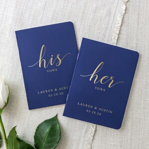 Pode incluir: Dois livros de votos azul marinho com letras douradas. O livro de cima diz "seus votos" e o livro de baixo diz "seus votos". Ambos os livros t&ecirc;m os nomes "Lauren & Austin" e a data "03-28-20" impressa neles.