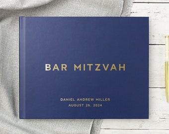 May include: A navy blue guest book with gold lettering that reads "Bar Mitzvah", "Daniel Andrew Miller", and "August 26, 2024".