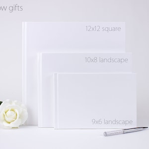 May include: Three white photo albums of different sizes. The largest album is 12x12 inches square, the middle album is 10x8 inches landscape, and the smallest album is 9x6 inches landscape.