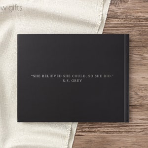 May include: Black hardcover journal with the quote "SHE BELIEVED SHE COULD, SO SHE DID." by R.S. GREY printed in white on the front cover.