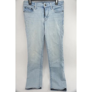 May include: Light blue denim jeans with a classic five-pocket design. The jeans have a straight leg fit and a button and zipper closure. The denim has a faded wash and subtle distressing for a worn look.
