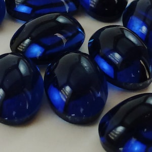 May include: A group of twelve oval-shaped, dark blue glass stones. The stones are smooth and shiny.