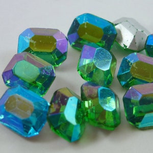 May include: Assortment of iridescent green and blue faceted glass gems. The gems are shaped like octagons and have a slightly rounded edge.