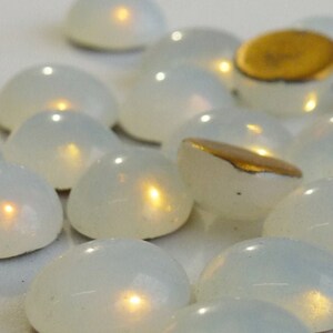 Peut inclure: Un groupe de lumières LED ovales blanches, alimentées par piles. Les lumières sont dispersées sur une surface blanche et émettent une lueur jaune chaude.