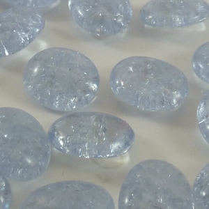 May include: A collection of light blue glass pebbles with a frosted finish. The pebbles are oval shaped and have a slightly irregular surface.