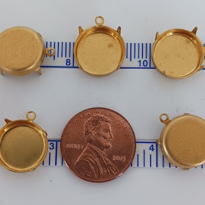 Puede incluir: Cinco bandejas de colgante de metal dorado de forma redonda con un bucle en la parte superior. Las bandejas tienen un diámetro de aproximadamente 2,5 cm y se muestran junto a un centavo estadounidense para la escala.