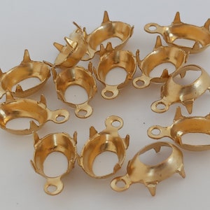Peut inclure: Une collection de fournitures de bijoux en métal doré. Chaque élément a une forme de coupe avec quatre griffes et une petite boucle. Ces composants sont probablement utilisés pour sertir des pierres précieuses ou d'autres éléments décoratifs en bijouterie.
