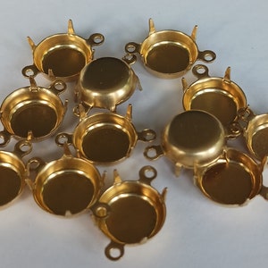 Puede incluir: Un grupo de 12 engastes de metal dorado para cabujones. Cada engaste tiene un centro redondo abierto y tres garras en el borde exterior. Los engastes están diseñados para sujetar una piedra de cabujón redonda.