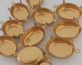 Puede incluir: Una colección de engastes biselados ovalados de color dorado para la fabricación de joyas. Cada engaste tiene forma de plato poco profundo con pequeñas puntas y bucles para sujetar. Los engastes están dispersos sobre una superficie blanca.