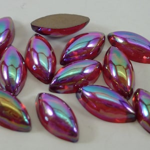 May include: A group of 12 iridescent red glass oval-shaped beads. The beads have a pearlescent finish and are scattered on a white surface.