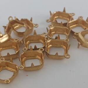 May include: A group of 10 gold-toned metal settings for bezel setting cabochons. Each setting has four prongs and two loops for attaching to jewelry.