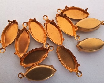 May include: Ten gold-colored metal settings for cabochons. Each setting has a loop at the top for hanging and two prongs on each side.