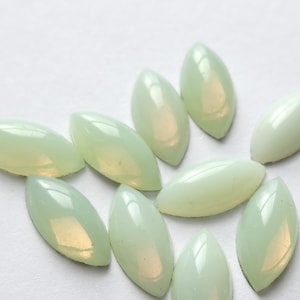 Può includere: Una collezione di dieci gemme di vetro di forma a marquise, di colore verde pallido e iridescenti.