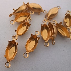 May include: A group of 10 gold-toned metal oval-shaped settings for cabochons. Each setting has two loops on the side for attaching to jewelry.