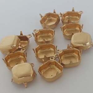 May include: Ten gold-toned metal settings for attaching rhinestones or other embellishments. Each setting has a square shape with rounded corners and six prongs.