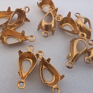 May include: A group of ten gold-tone metal teardrop-shaped pendant settings with two loops on each setting.