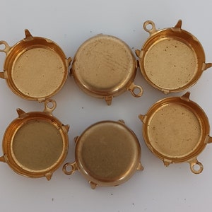 May include: Six gold-toned metal round bezel settings with prongs and a loop for hanging. The bezels are designed to hold a round cabochon stone.