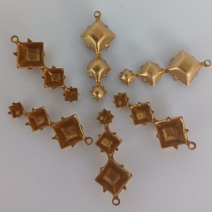 May include: Set of six gold-tone metal diamond-shaped embellishments. Each embellishment has a loop at the top for attaching to a project.