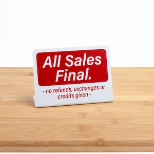 May include: White sign with red text that reads "All Sales Final."  The sign also includes the text "no refunds, exchanges or credits given."