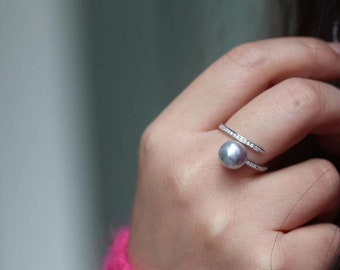 May include: A silver ring with a large gray pearl and a band of small diamonds.