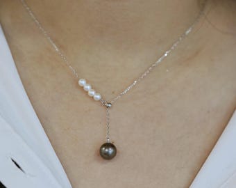 May include: A silver chain necklace with a single large dark brown pearl pendant and a row of smaller white pearls.