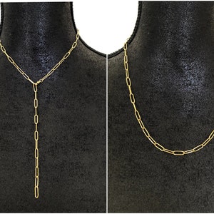 Puede incluir: Dos collares de cadena de oro en un maniquí negro. El collar de la izquierda es una cadena larga y fina con un colgante en forma de Y. El collar de la derecha es una cadena más corta y gruesa.