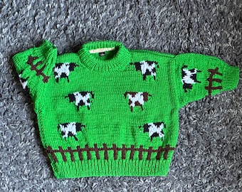 Jersey infantil de vaca en color verde. Edad: 2-3 años. Tejido a mano en el Reino Unido.