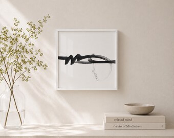 May include: A framed abstract art print featuring a black ink design on a white background. The artwork has a minimalist style with a bold, flowing line and a circular shape. The frame is white.