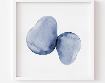 May include: A square white frame containing an abstract watercolor painting. The artwork features two overlapping, organic, blob-like shapes in varying shades of indigo blue, displaying soft, translucent edges and textured pigment gradients.