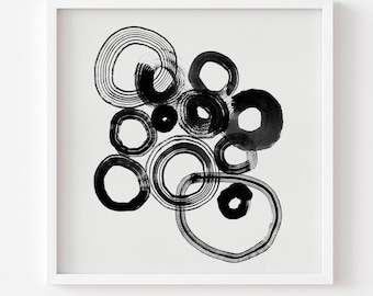 May include: Abstract black and white art print featuring a collection of overlapping circles. The circles vary in size and are created with brushstrokes, giving them a textured appearance. The artwork is framed in a white square frame.
