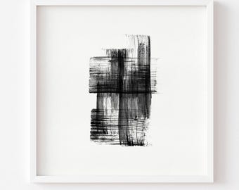 May include: A square white frame containing a piece of wall art featuring a central abstract design composed of layered black ink brushstrokes. The strokes create a cross-like pattern with varying levels of transparency and texture on a white background.