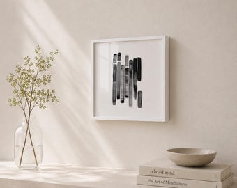 May include: A framed abstract art print featuring vertical brushstrokes in shades of gray and black. The artwork is displayed in a white frame, creating a minimalist aesthetic. The print is mounted on a neutral-toned wall, with a vase of greenery and books nearby.