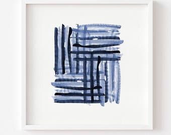 May include: A square white frame containing an abstract watercolor painting. The artwork features a series of intersecting horizontal and vertical brushstrokes in varying shades of deep navy blue and lighter indigo, creating a grid-like pattern.