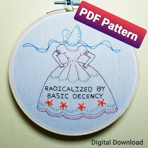 Könnte beinhalten: Ein Stickrahmen mit einem handgenähten Design. Das Design zeigt eine Figur in einem Kleid mit dem Text "RADICALIZED BY BASIC DECENCY". Die Stickerei ist in Blau-, Lila- und Orangetönen gehalten. Die Wörter "PDF Pattern" und "Digital Download" sind ebenfalls sichtbar.