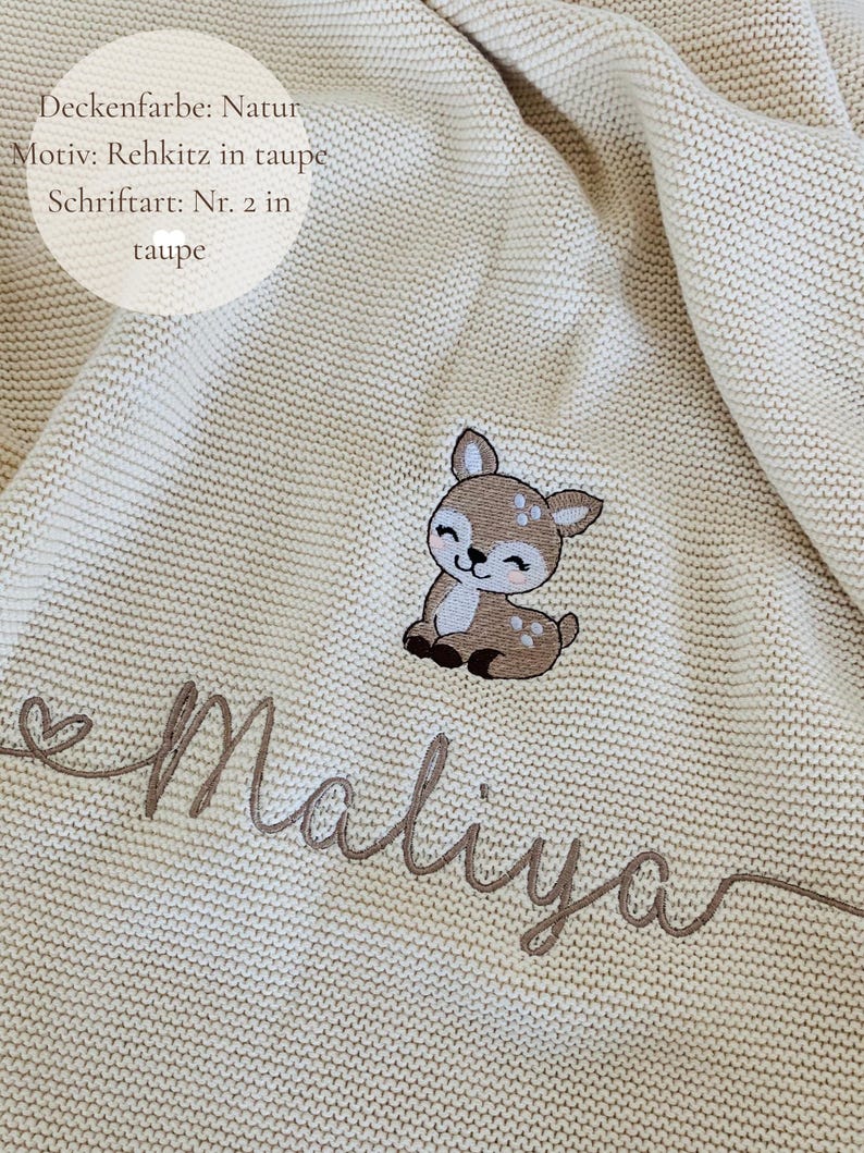 May include: A natural-colored knit blanket featuring an embroidered taupe fawn graphic and the name Maliya in cursive taupe script. Text on the blanket reads: Deckenfarbe: Natur, Motiv: Rehkitz in taupe, Schriftart: Nr. 2 in taupe.