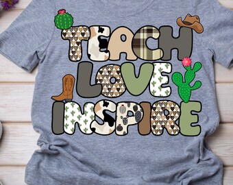 May include: A heather gray t-shirt with the words "TEACH LOVE INSPIRE" in a colorful, patterned design. The letters feature cowboy boots, hats, cacti, and various patterns. The shirt is made of a soft material.