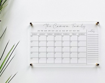 May include: A clear acrylic dry erase calendar with the text "The Cameron Family." The calendar has a grid for each month of the year, with spaces for notes.