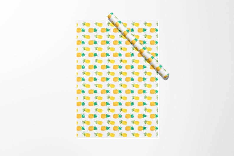 May include: White wrapping paper with a repeating pattern of yellow and green watercolor pineapples. A rolled-up section of the same paper is positioned diagonally across the top of the sheet.
