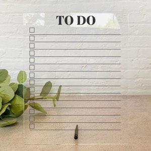 May include: A clear acrylic to-do list board with black lines and checkboxes. The board has the words "TO DO" printed in black at the top.