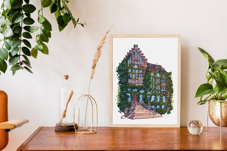 May include: A framed print of a watercolor painting depicting a brick building with ivy growing on the exterior. The building has a steep roof and many windows. The building is surrounded by green trees and bushes. The building has a set of stairs leading up to the entrance.