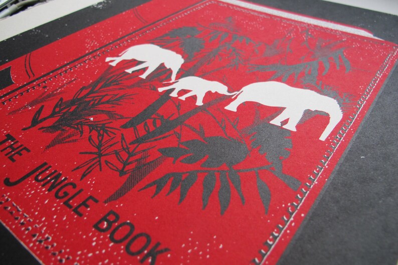 May include: Red and black illustration of elephants walking through a jungle with the text "The Jungle Book" printed on the bottom left corner.