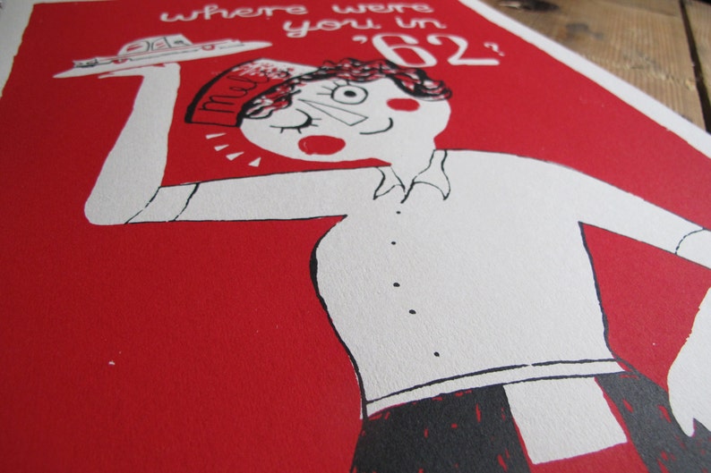 May include: A red and white illustration of a person wearing a hat with the word "mom" on it. The person is holding a tray with a small car on it. The text "where were you in '62?" is written above the person.