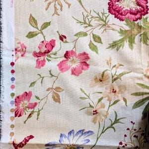May include: Cream-coloured floral fabric with a pattern of pink, red, and blue flowers, green leaves, and brown stems. The flowers vary in size and style, creating a classic, vintage aesthetic. The fabric is suitable for various craft projects.