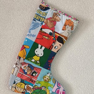 Può includere: Una calza natalizia patchwork realizzata con vari tessuti colorati con personaggi dei cartoni animati stampati, tra cui Alf, Saetta McQueen, Miffy, Bob aggiustatutto e un Teletubby. La calza ha un bordo floreale e un gancio per appenderla.