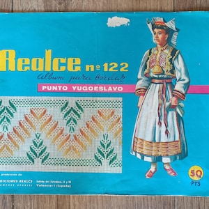 Può includere: Una copertina di libro vintage con il titolo "Realce no 122" in lettere gialle su sfondo turchese. La copertina presenta un'illustrazione di una persona in abiti tradizionali e un motivo a punto croce. È visibile anche il testo "Album para bordar".
