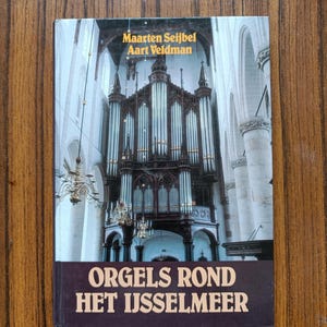 Könnte beinhalten: Ein Buch mit dem Titel "Orgels Rond Het IJsselmeer" von Maarten Seijbel und Aart Veldman. Der Umschlag zeigt ein Foto einer großen Orgel in einer Kirche.